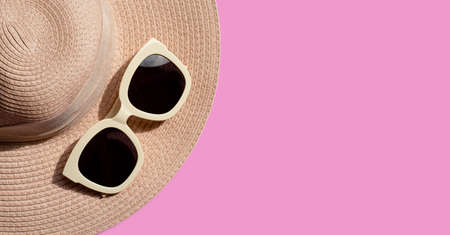 Sunglasses with summer hat on pink background. Enjoy holiday concept. Copy space