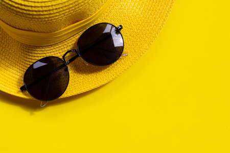 Sunglasses with summer hat on yellow background. Enjoy holiday concept. Copy spaceの写真素材