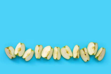 Green apple slices on blue background. Copy spaceの写真素材