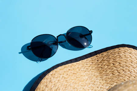 Sunglasses with summer hat on blue background. Enjoy holiday concept. Copy spaceの写真素材