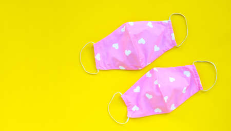 Handmade pink and heart shape cloth masks on yellow background. Copy spaceの写真素材