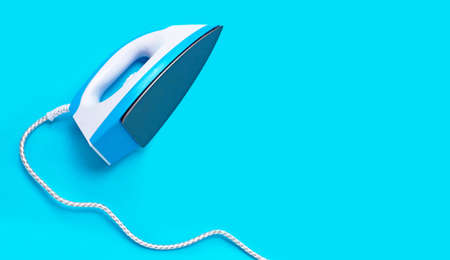 Iron on blue background. Top view with copy spaceの写真素材