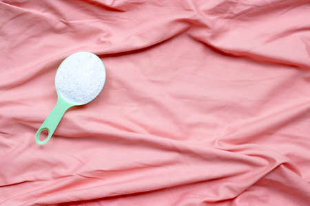 Detergent powder in measuring spoon in pink cloth before washing. Laundry concept.の写真素材