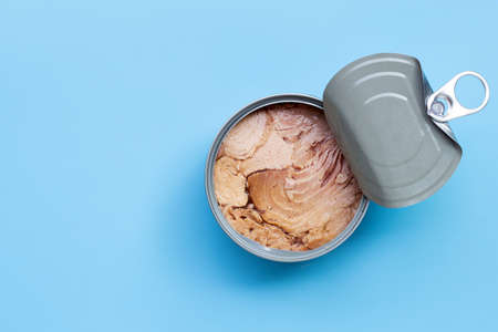 Canned tuna fish on blue background. Copy space