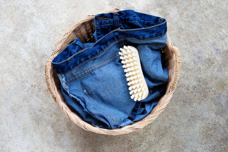 Jeans in laundry basket on cement floor background. Top view