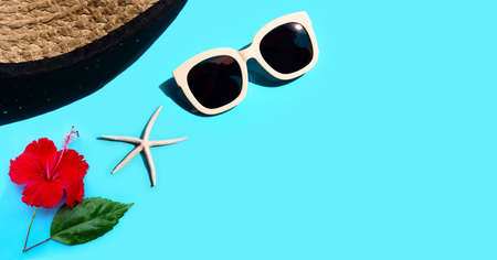Summer hat with sunglasses, hibiscus flower and starfish on blue background. Enjoy holiday concept. Copy spaceの写真素材