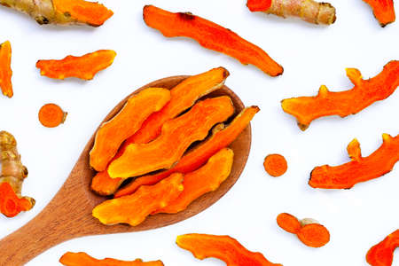 Cutting of turmeric roots on wooden spoon on white background.