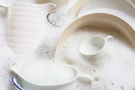 Washing dishes, Close up of utensils soaking in kitchen sink.