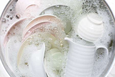 Washing dishes, Close up of utensils soaking in kitchen sink.