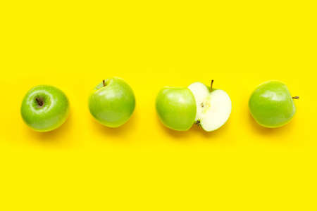 Green apples on yellow background. Top view