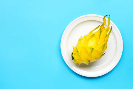 Yellow pitahaya or dragon fruit on white plate on blue background. Copy spaceの写真素材