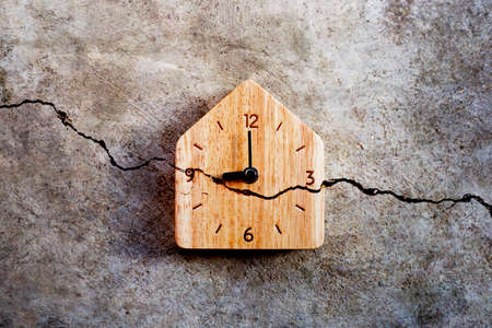 Wooden clock on cracked cement wall texture background. Top viewの写真素材