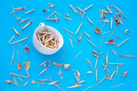 Organic dried lemongrass in white cup on blue background. Herbal tea conceptの写真素材