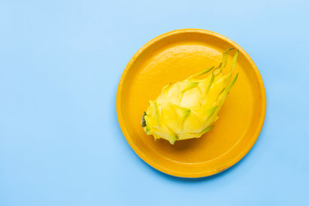 Yellow pitahaya or dragon fruit on yellow plate on blue background. Copy spaceの写真素材
