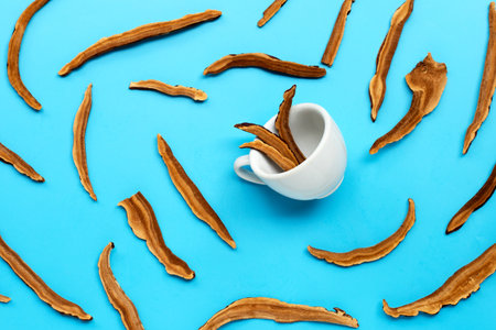 Dried lingzhi mushroom slices with cup on blue background. Top viewの写真素材