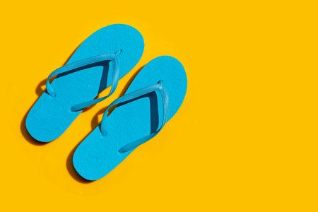 Blue flip flops on yellow background. Enjoy summer holiday concept.の写真素材
