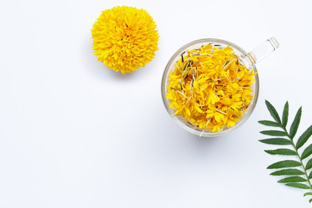 A glass cup with marigold flower petals on white background. Flower herbal tea concept.の写真素材