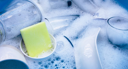Washing used drinking glasses and cups with yellow sponge