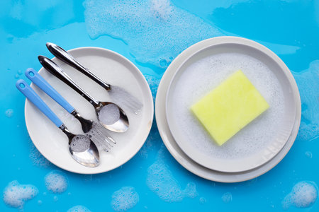 Washing dishes on blue with soapy foamの写真素材