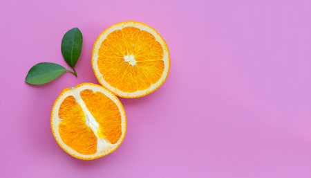 Fresh orange fruit with green leaves on pinkの写真素材