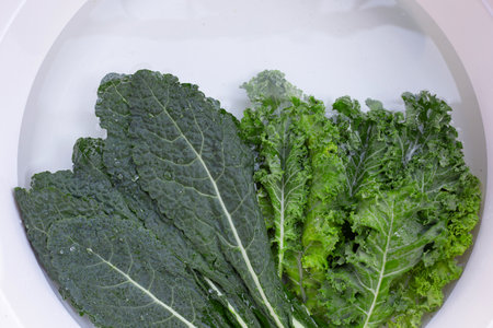 Fresh kale leaves soaked in a white bowl of water.