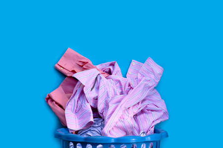 Clothes with a laundry basket on blue background. Copy spaceの写真素材