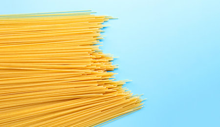 Yellow long spaghetti on blue background. Copy spaceの写真素材