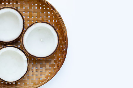 Half coconuts on wooden bamboo threshing basket on white background. Copy spaceの写真素材