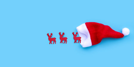 Santa hat with reindeers on blue background. Copy spaceの写真素材