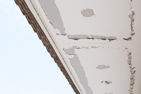 White color paint peeling off on ceiling house. Under the roof