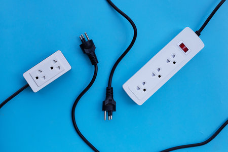 Electrical power strip and plug on blue background. Top view