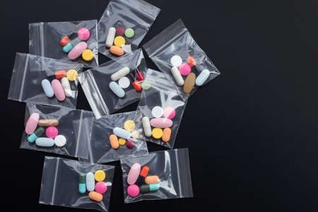 Colorful tablets with capsules and pills in medicine plastic zip lock bags on dark background. Top viewの写真素材
