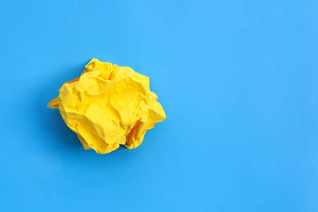 Crumpled yellow paper ball on blue background. Top viewの写真素材