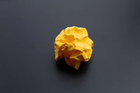 Crumpled yellow paper ball on dark background. Copy spaceの写真素材
