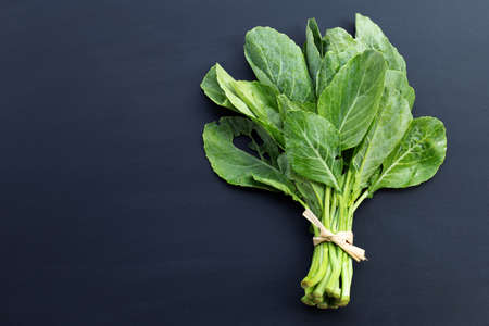 Collard green leaves with holes, eaten by pest. Organic Vegetable on dark background.の写真素材