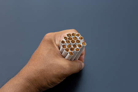 Hand holding cigarette on dark background. Non smoking for health conceptの写真素材