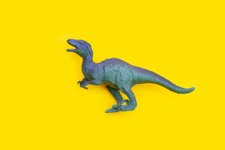 Plastic dinosaur toy on yellow background.の写真素材