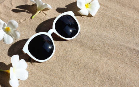 Sunglasses with white plumeria flower on sand.  Summer background concept.の写真素材