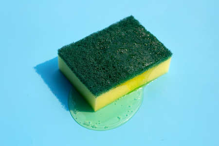 Kitchen sponge with dish washing liquid on blue background.の写真素材