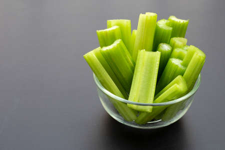 Fresh celery in glass bowl on dark background.の写真素材