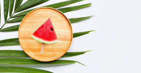 Watermelon slice  on wooden plate on tropical palm leavesの写真素材