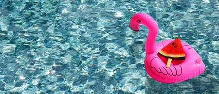 watermelon slice on inflatable of pink flamingo ring floating in swimming pool
