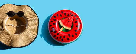 Summer hat and sunglasses with watermelon slice on swim ring toy on blue background. Summer background conceptの写真素材