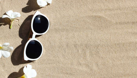 Sunglasses with white plumeria flower on sand.  Summer background concept.の写真素材