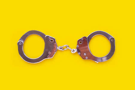 Metal handcuffs on yellow backgroundの写真素材
