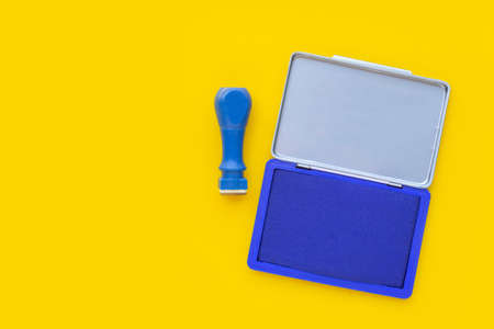 Rubber stamp with stamp pad on yellow background.の写真素材