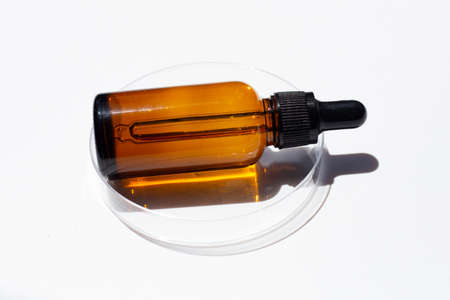 Brown bottle eye dropper in petri dish on white background.の写真素材