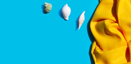 Yellow women's shawl with seashells on blue background. Copy spaceの写真素材