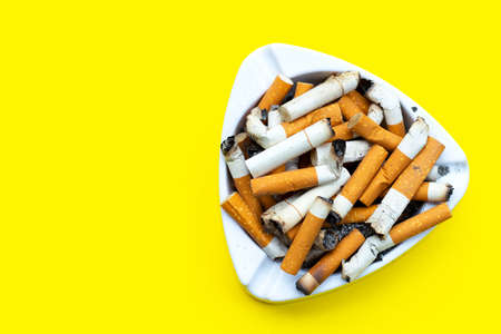 Ashtray and cigarettes on yellow background. Copy spaceの写真素材