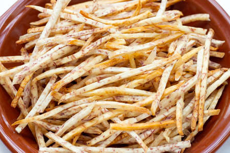 Fried taro sticks in bowl on white background.の写真素材